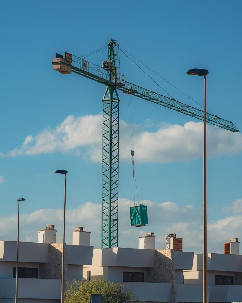 A tower crane at an urban construction site against a blue sky.