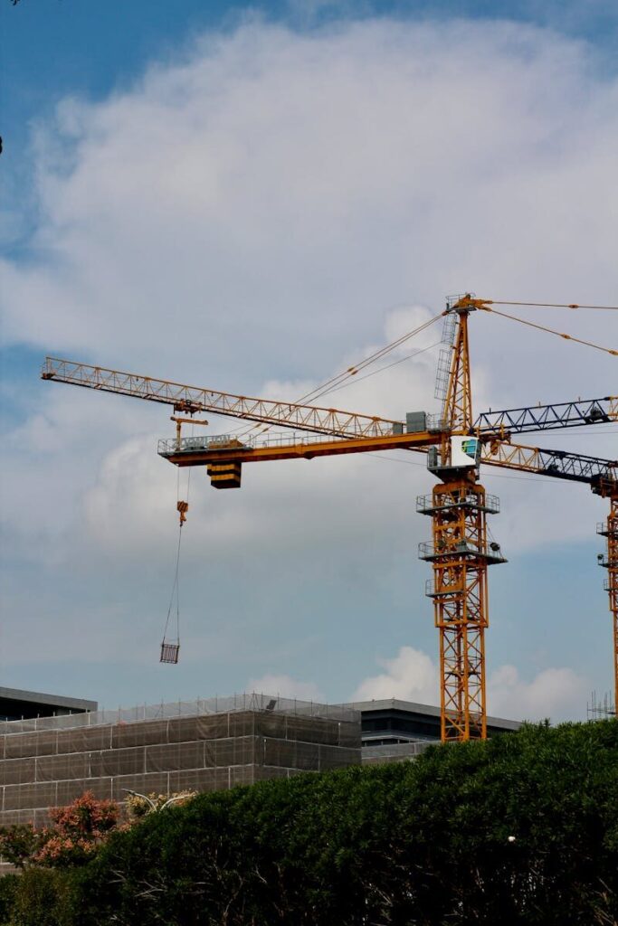 Tower crane operating at an urban construction site under a blue sky, symbolizing growth and development.